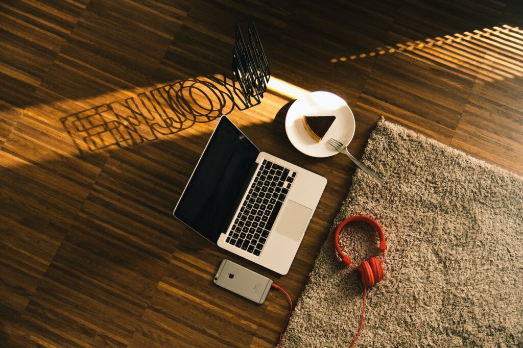 macbook beside slice on cake on plate iphone and headphones